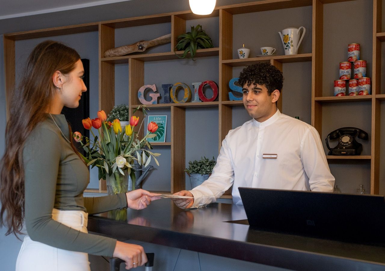 A reception desk with a person handing over a card to another person.