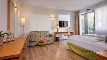 Ein Hotelzimmer mit Bett, Sofa, Schreibtisch und Fernseher.