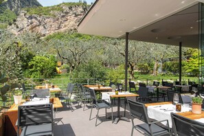 Zona pranzo all'aperto con tavoli e sedie, con vista su un paesaggio montuoso.