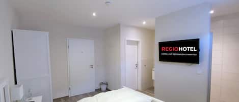 A hotel room with a bed, a TV, and a wall-mounted sign.