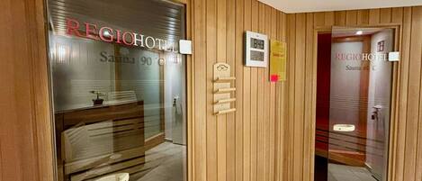 Entrada de hotel con un letrero de sauna, una recepción y un diseño de pared de madera.