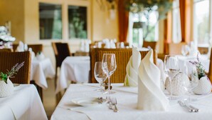 A dining area with tables set for a meal, featuring white tablecloths, silverware, and wine glasses. - Regiohotel Naturresort Ilsenburg  (Ilsenburg)