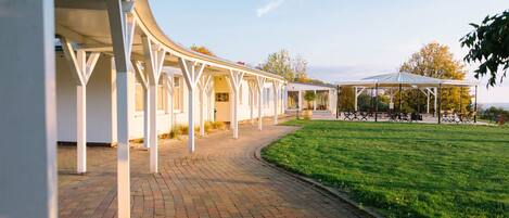 A covered outdoor area with a brick pathway leading to a seating area under a pavilion.