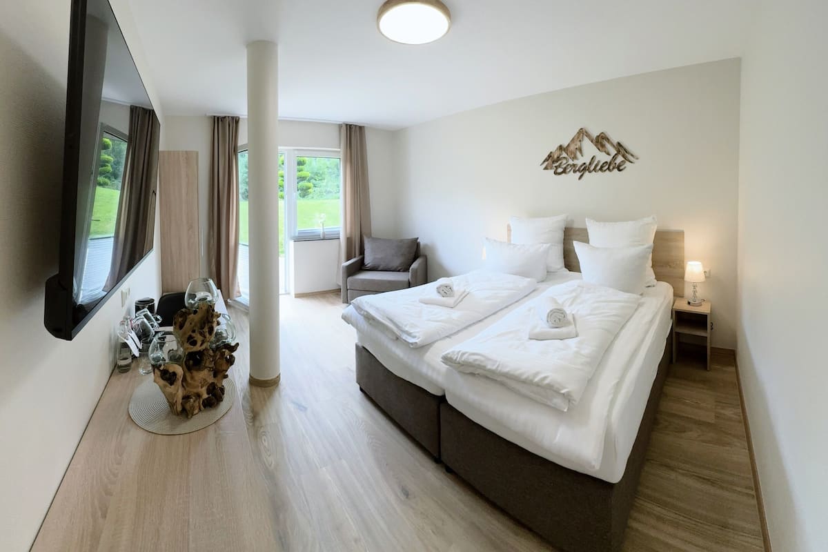 Une chambre d’hôtel équipée d’un lit, d’une télévision, d’une chaise, d’une lampe et offrant une vue sur l’extérieur.
