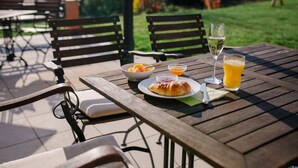 A wooden table with a plate of food, a glass of juice, and a glass of white wine. - Regiohotel Naturresort Ilsenburg  (Ilsenburg)