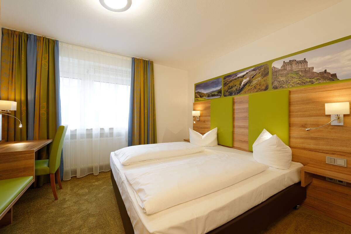 A hotel room with a bed, a desk, and a chair.