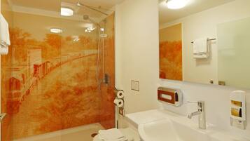 Un baño moderno con cabina de ducha de vidrio, un lavabo blanco y un inodoro.