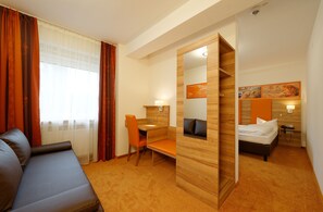 A hotel room with a sofa, a desk with a chair, a bed, and a large mirror. - Hotel Gasthof Zur Post (Leipheim)