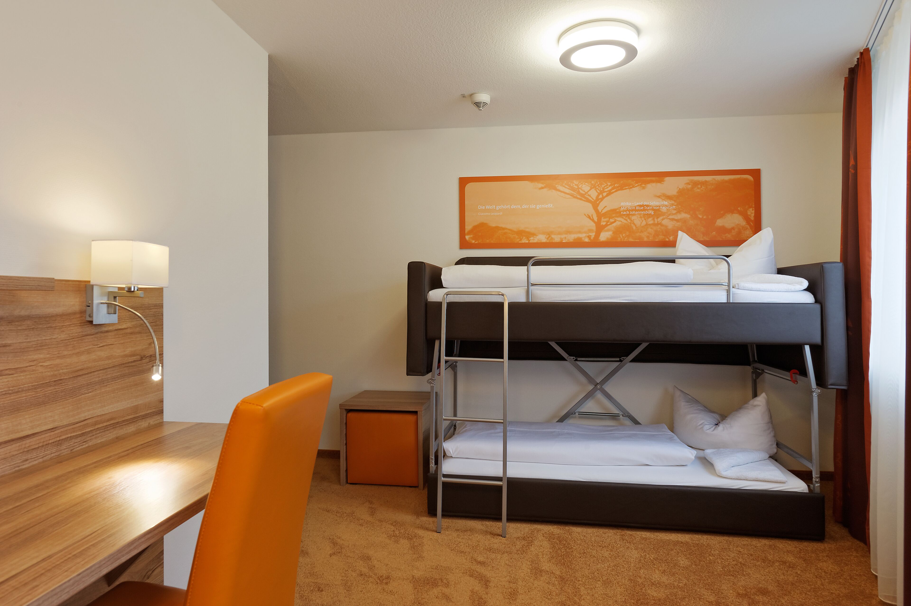 A compact hotel room with a bunk bed, a desk, and a chair.