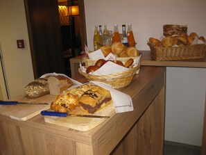 A variety of breads and pastries on a wooden counter, with bottles of beverages in the background. - Hotel Gasthof Zur Post (Leipheim)