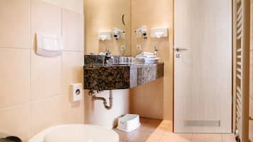 Een badkamer met toilet, wastafel, handdoekhouder en douche.