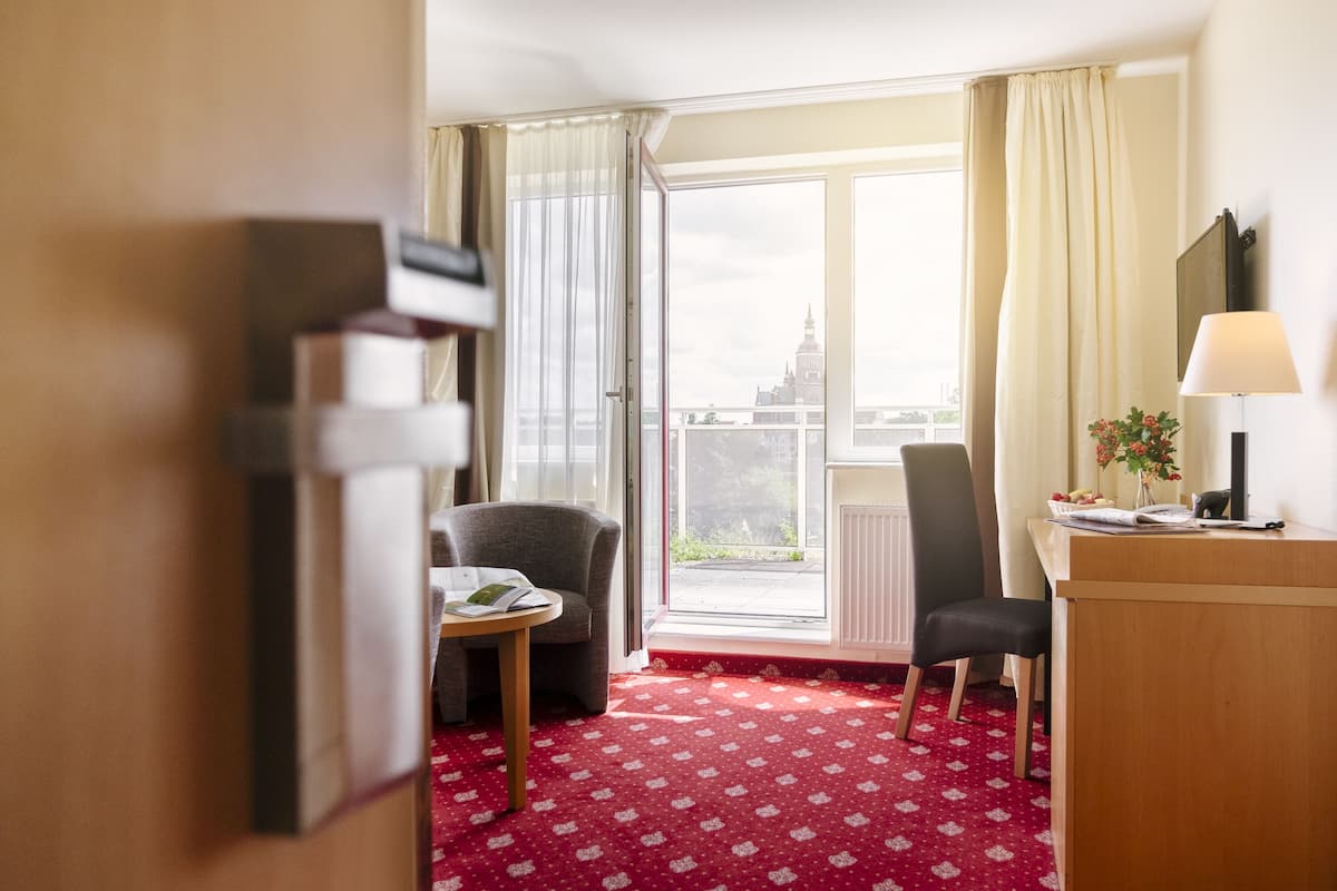 Una habitación de hotel con un ventanal grande, un escritorio, una silla y una mesita.