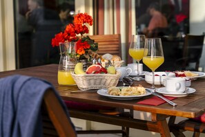A table set for breakfast with a wicker basket, fruit, and two glasses of orange juice.