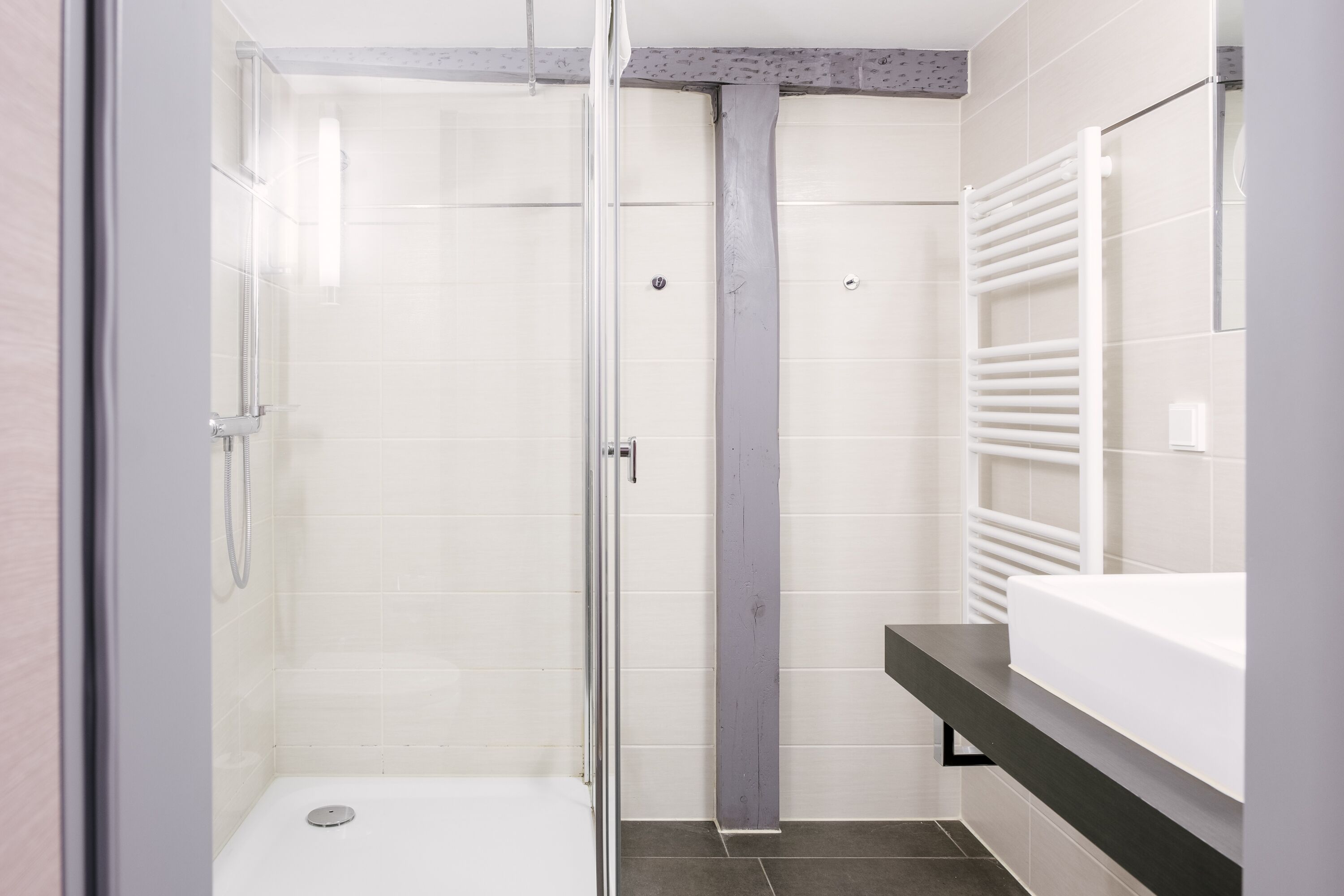 Un bagno moderno con cabina doccia in vetro, un lavandino bianco e un porta asciugamani.