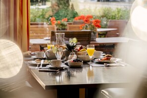 Mesa de desayuno con diferentes platos, entre ellos frutas, bebidas y una jarra.