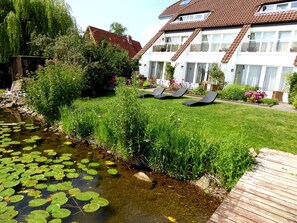 A residential area with a pond, lush greenery, and a white building with a brown roof. - Hotel Der Seehof (Ratzeburg)