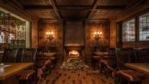 A cozy restaurant interior with wooden paneling, a brick floor, and a central fireplace. - Hotel Der Seehof (Ratzeburg)
