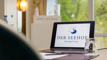 Ein Laptop auf einem Schreibtisch, der ein Hoteldrehschild mit dem Namen "DER SEEHOF" und dem Slogan "Das Hotel im See" zeigt.