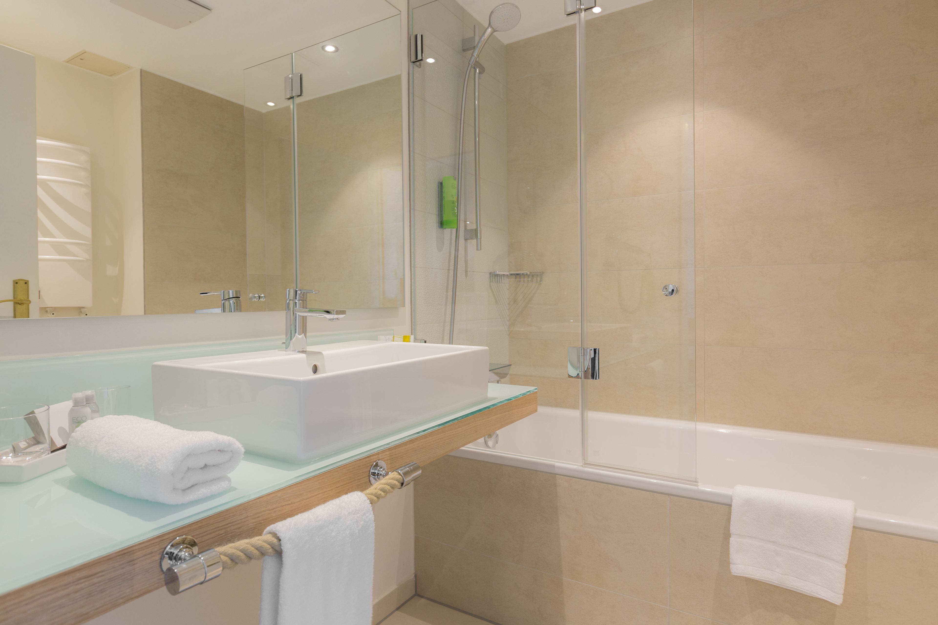 Ein modernes Badezimmer mit einem Glaswaschtisch, einer einteiligen Glasdusche und einer separaten Badewanne.
