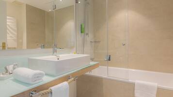 Ein modernes Badezimmer mit einem Glaswaschtisch, einer einteiligen Glasdusche und einer separaten Badewanne.