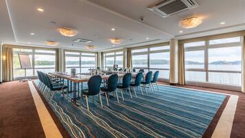 A conference room with a large table, chairs, and a view of a lake.