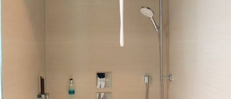 A shower with a wooden bucket, a handheld showerhead, and a handheld hose.