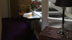 A room with a window, a chair, a small table with a vase of flowers, and a lamp. - Hotel De Weyman (Santpoort-Noord)