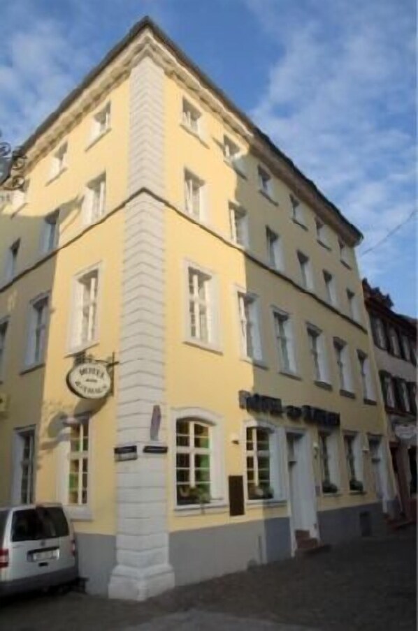 A yellow building with multiple windows and a sign that reads "Hotel".