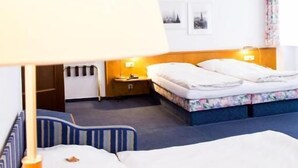 A hotel room with a bed, a desk, a chair, and a lamp.