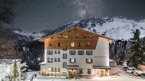Un hotel con fachada de madera, múltiples ventanas y un letrero que dice "HOTEL ALPENSONNE".