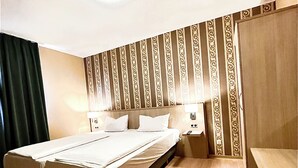 A hotel room with a large bed, a bedside table, a nightstand, and a wooden floor. - Hotel Hafner (Stuttgart)