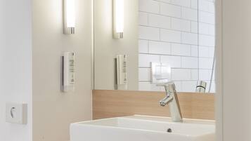 Un baño moderno con un espejo grande, un lavabo blanco y un mueble de tocador de madera.