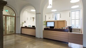 Un espace d’accueil au design moderne, comprenant un comptoir d’accueil, un écran d’ordinateur et une fenêtre laissant entrer la lumière naturelle.