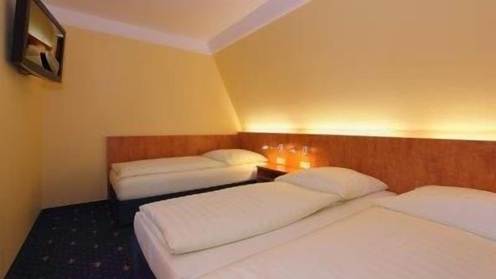 Una habitación de hotel con dos camas, un cabecero de madera y una mesita de noche con una lámpara.