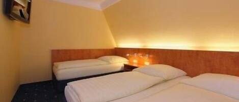 Una habitación de hotel con dos camas, un cabecero de madera y una mesita de noche con una lámpara.