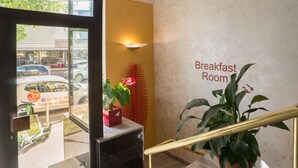 A breakfast room with a sign, a potted plant, and a view of the street outside. - Hotel Astro (Stuttgart)