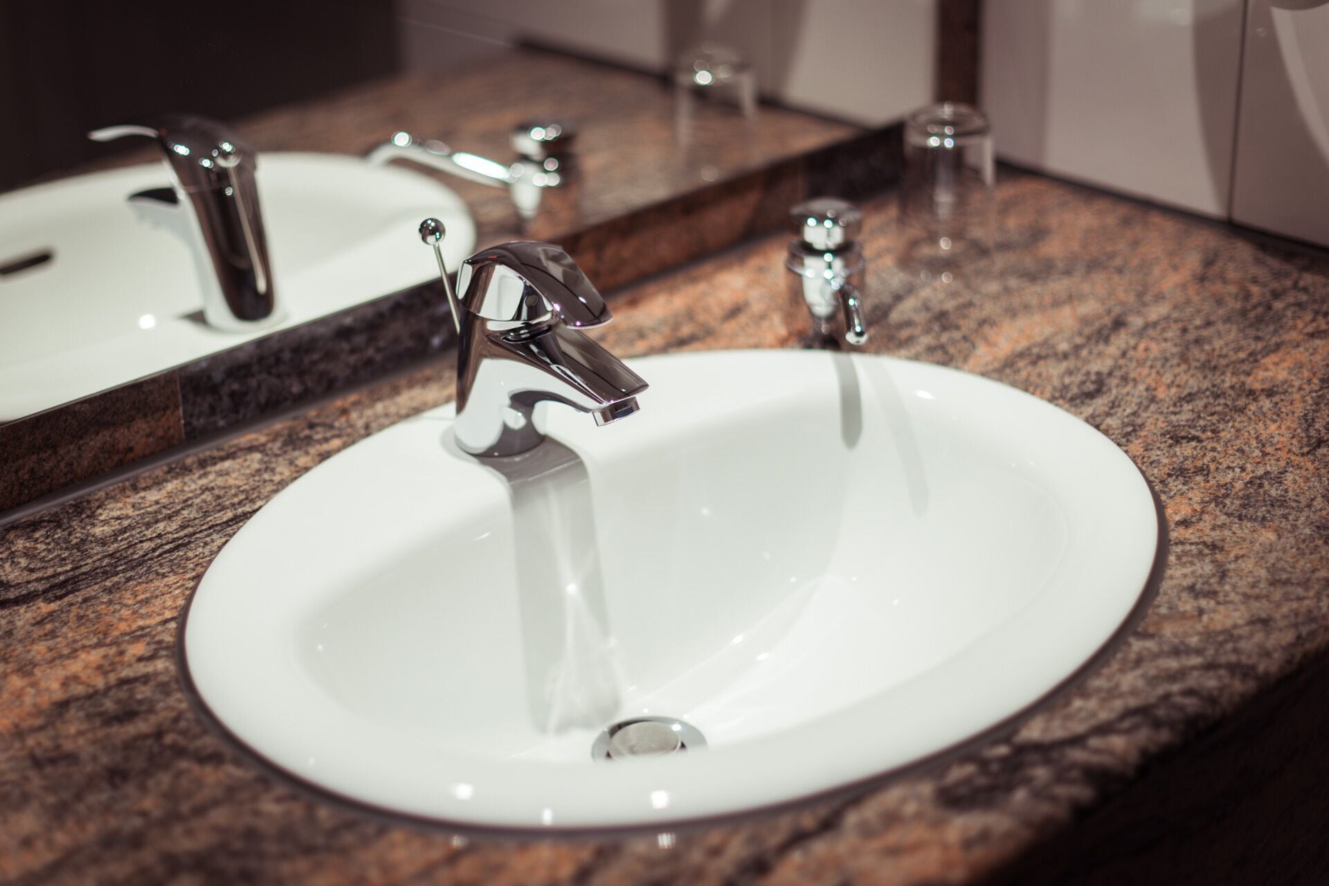 A white sink with a single chrome faucet and a mirror above it.