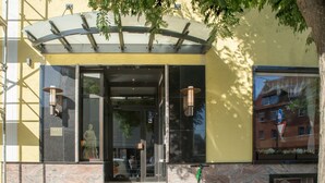 A building entrance with a glass canopy, a statue, and a green scooter parked outside. - Hotel Astro (Stuttgart)