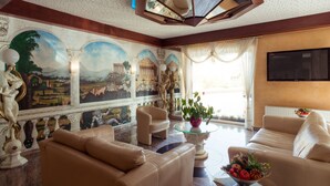 A spacious living room with a large mural, comfortable seating, and a modern entertainment system. - Hotel Astro (Stuttgart)