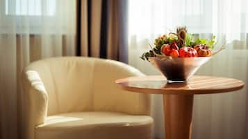 A round wooden table with a glass bowl containing a variety of fresh vegetables and herbs.