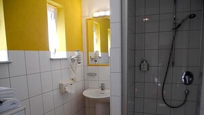Ein Badezimmer mit Dusche, Waschbecken und Spiegel.