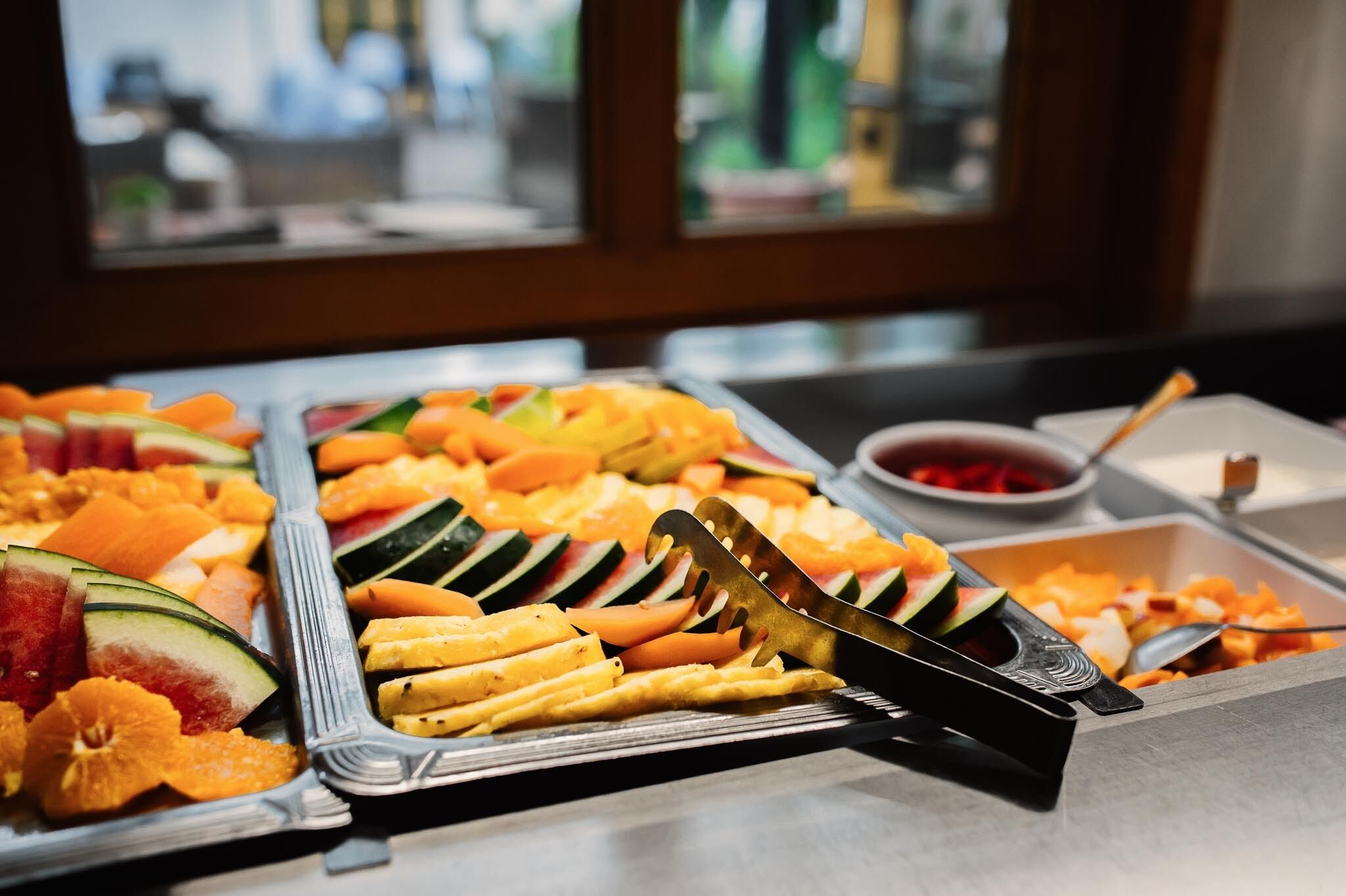 Un buffet con diversi tipi di frutta e verdura, tra cui anguria, arance e cetrioli.
