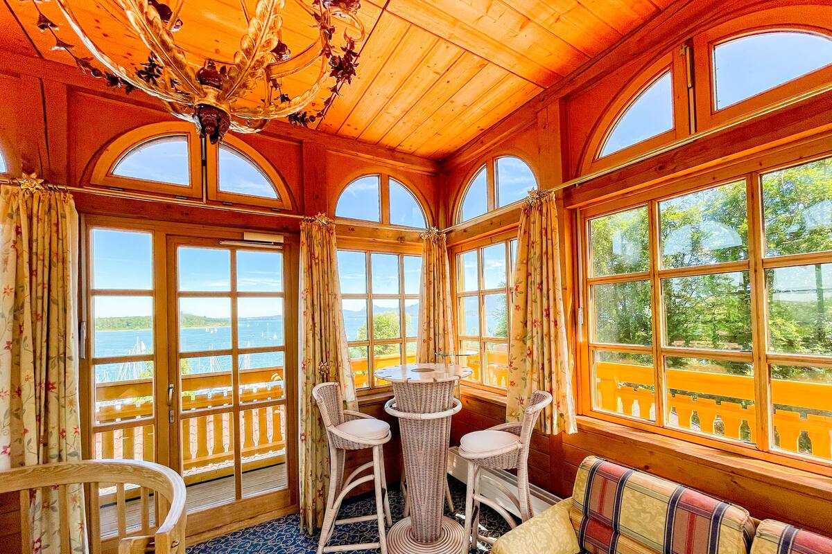 Une pièce chaleureuse avec de grandes fenêtres, un plafond en bois et une vue sur la mer.