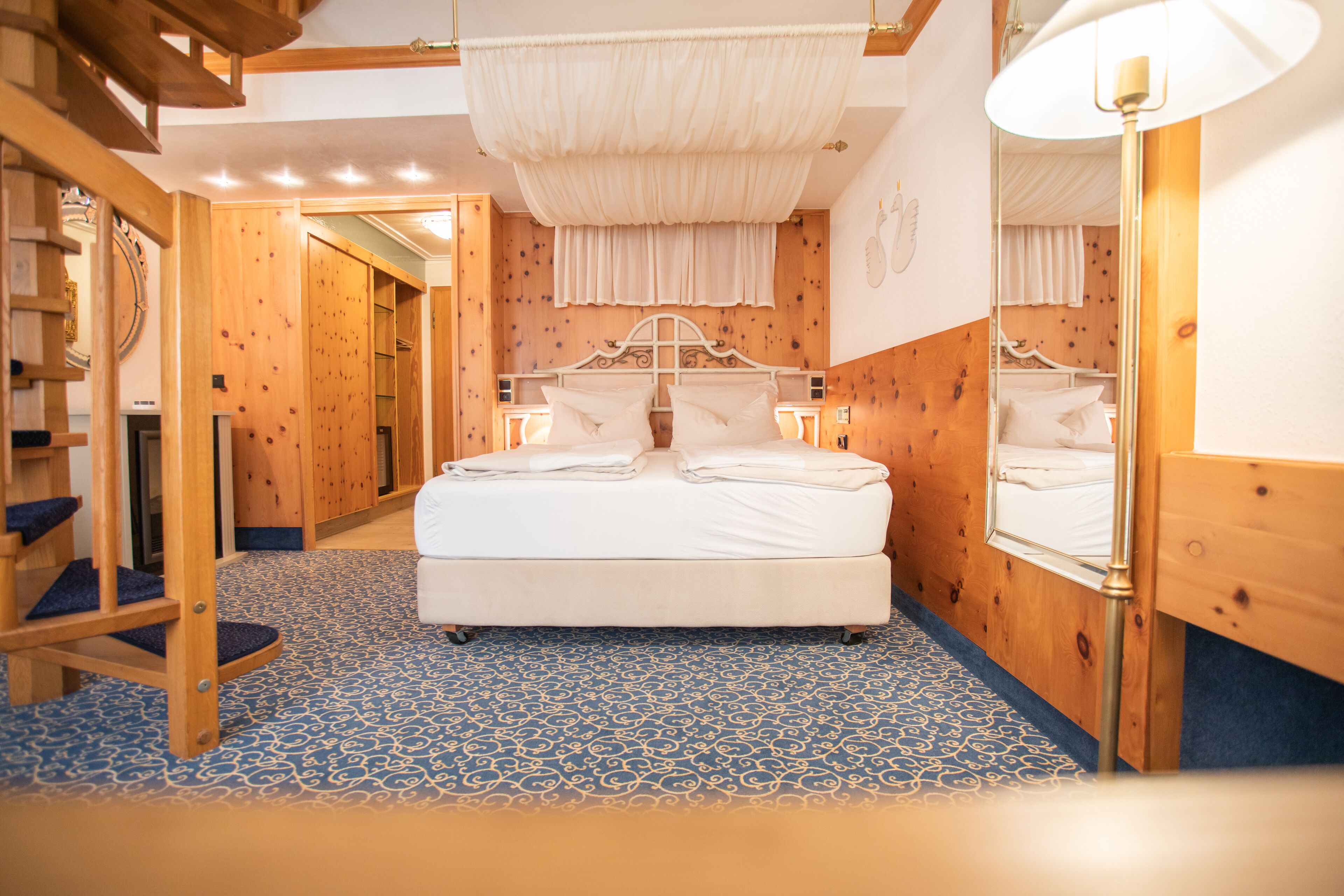 Un dormitorio con una cama grande, paredes de madera y un suelo estampado.