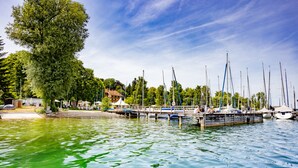 Een jachthaven met aangemeerde boten, een houten steiger en een grote boom.