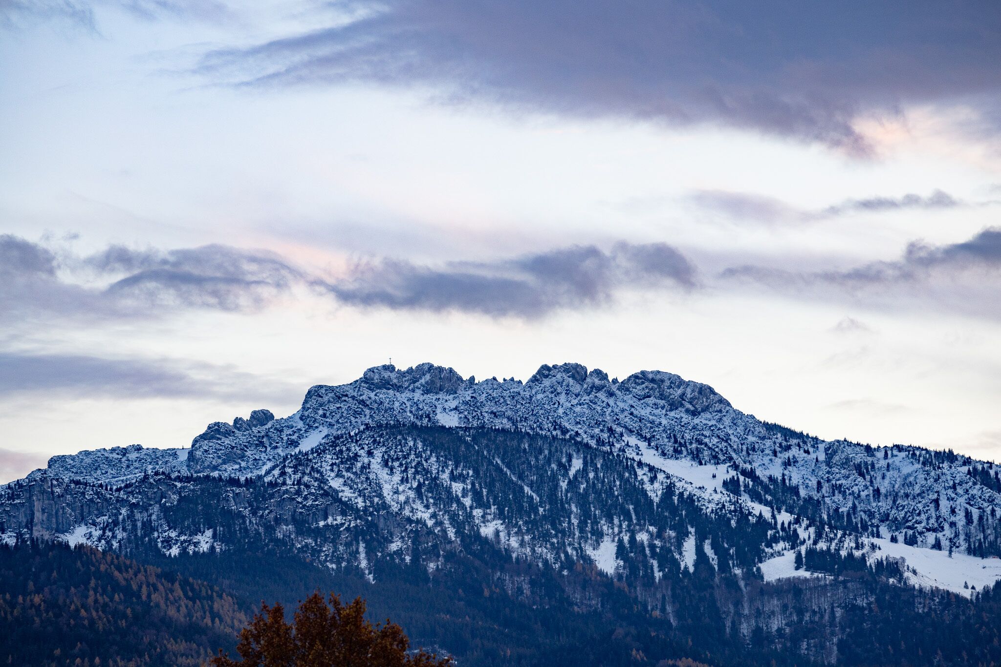 A mountain landscape with snow-covered peaks and a forested valley.