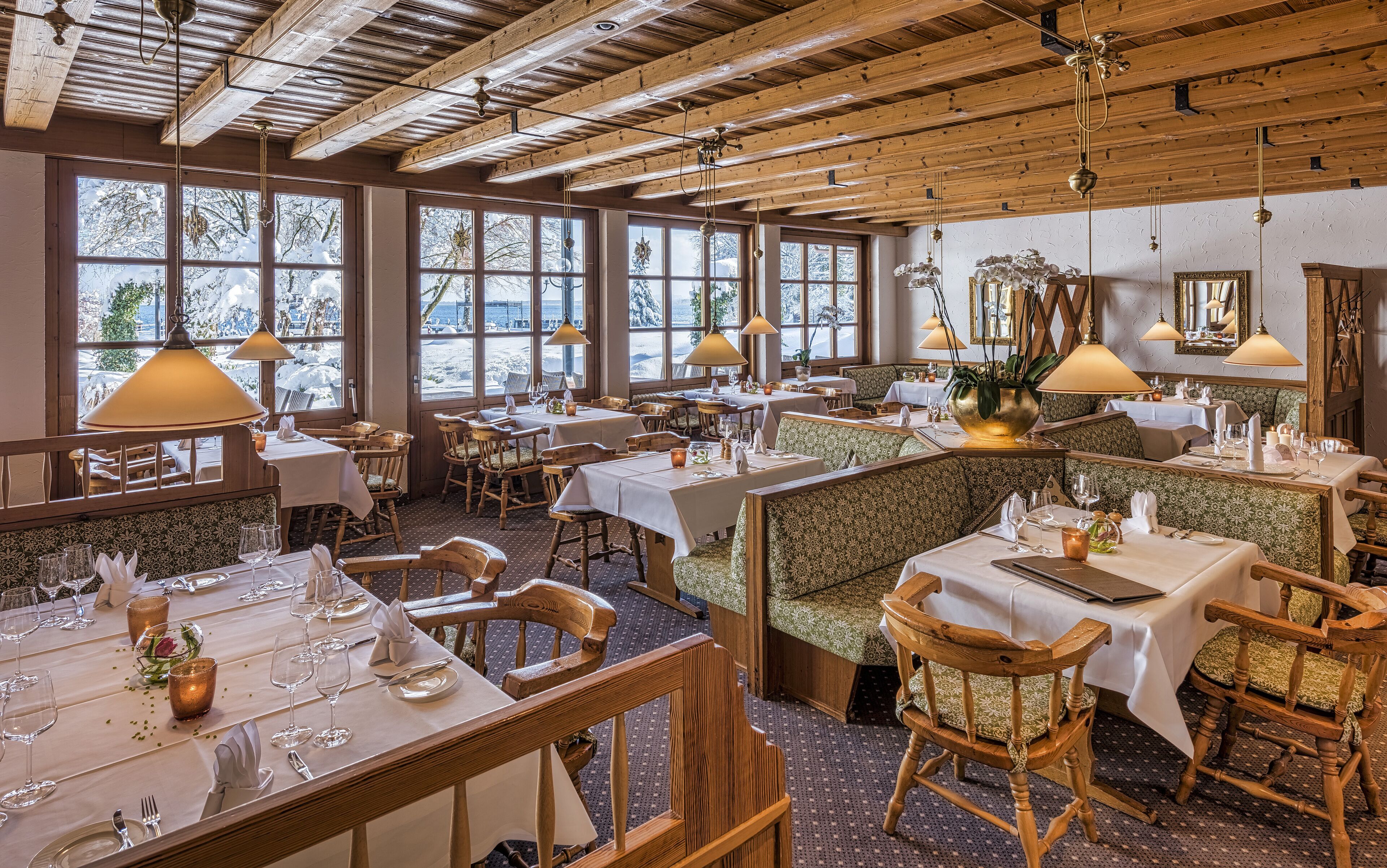 Un restaurante con vigas de madera, ventanas amplias y mesas dispuestas para comer.