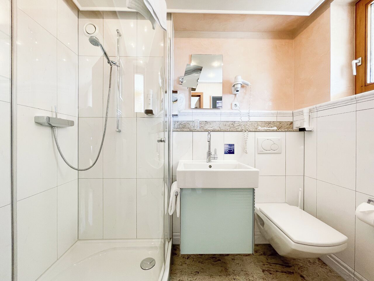 Un baño con ducha acristalada, lavamanos e inodoro.