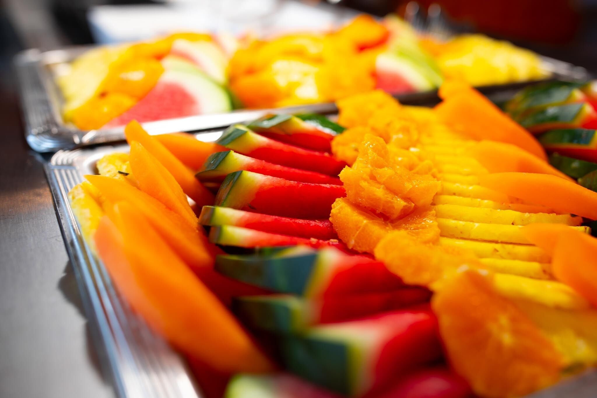 A buffet with various fruits like watermelon, mango, and pineapple.