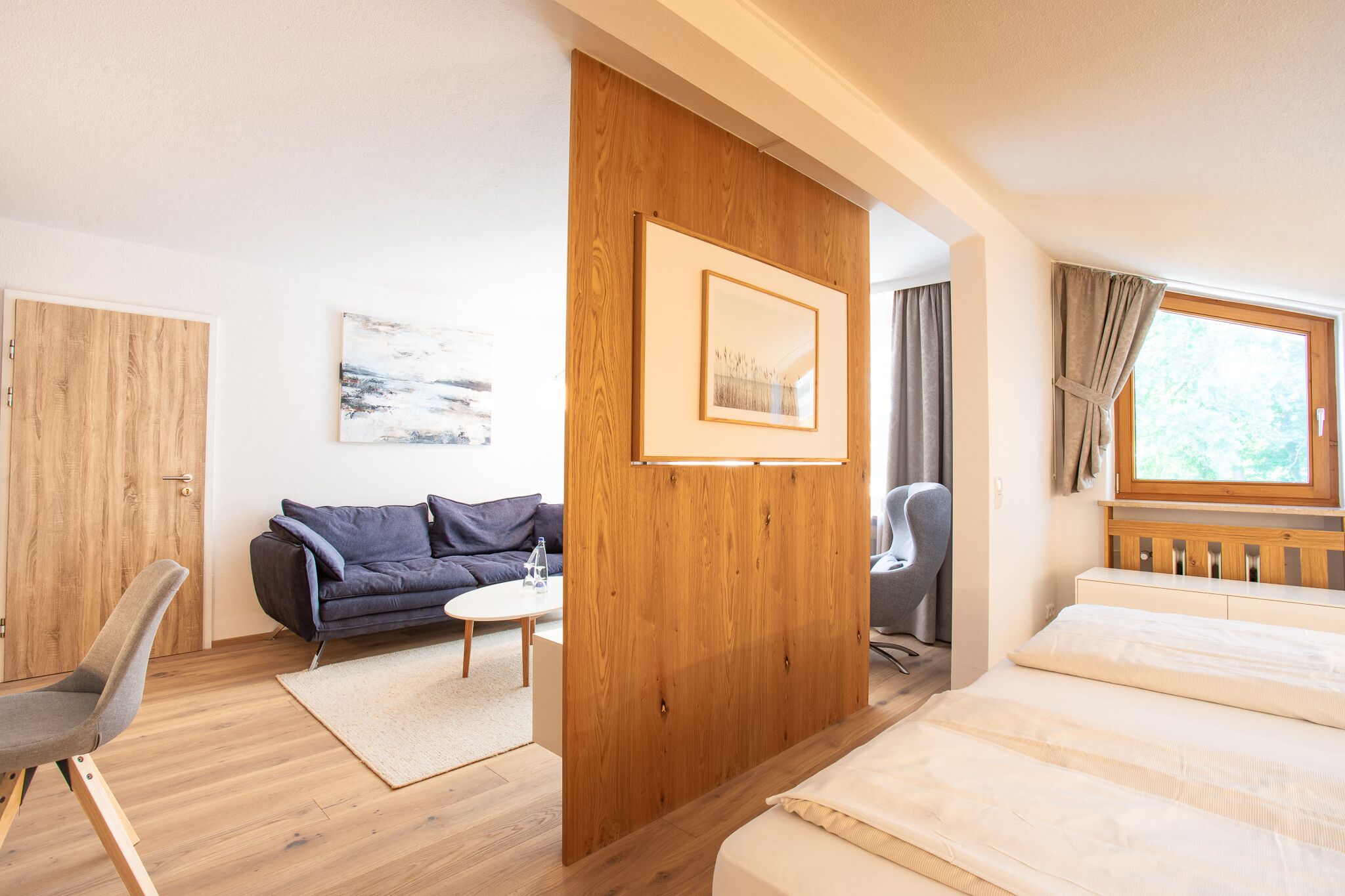 Ein modernes Zimmer mit einem Bett, einer Couch, einem Sessel und einer Holzwand.